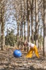 Sereno adulto embarazada entrenamiento con pilates pelota en el parque durante el tiempo soleado - foto de stock