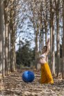 Доросла вагітна жінка практикує пілатес з синім м'ячем у парку під час сонячного дня — стокове фото