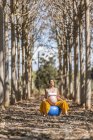 Expectant mother doing pilates exercise while sitting on big elastic blue fit ball in autumn forest glade — Stock Photo