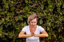 Erwachsene Frau meditiert in der Nähe von Busch — Stockfoto