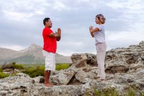 Coppia meditando sulla roccia — Foto stock