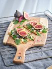 Hausgemachte offene Sandwiches mit Feigen- und Käsescheiben auf Roggenbrot mit Rucola auf Holzbrett — Stockfoto