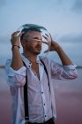 Homme pensif en chemise mouillée avec aquarium vide sur la tête debout et contemplant par mer calme au crépuscule — Photo de stock