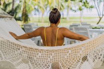 Rückansicht einer Frau im Badeanzug, die in der Hängematte am exotischen Meer in Costa Rica sitzt — Stockfoto
