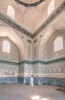 Mujer admirando los ornamentos en las paredes del antiguo edificio mientras visita Samarcanda, Uzbekistán - foto de stock