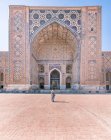 Visão traseira da mulher irreconhecível em pé na entrada do edifício ornamental gasto Registan em Samarcanda, Uzbequistão — Fotografia de Stock