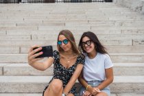 Laughing women taking selfie on stairs at old building — Stock Photo