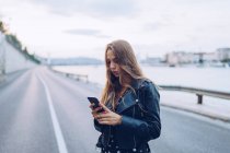 Long-haired stylish woman browsing smartphone in Budapest — Stock Photo