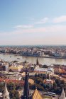Helle Flusslandschaft unter bewölktem Himmel mit Häusern und Gebäuden der Stadt in Budapest — Stockfoto