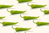 Dall'alto composizione creativa di pepe intero verde a fette su superficie bianca — Foto stock