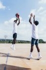 Vista lateral de caras afro-americanos jogando basquete em dia brilhante no campo de jogos — Fotografia de Stock