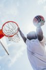 Kraftvoller, energiegeladener afrikanisch-amerikanischer Sportler hängt auf Basketballrunde, nachdem er Ball in Netz auf Spielplatz geschossen hat — Stockfoto