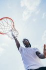 Poderoso atleta afro-americano enérgico pendurado na volta de basquete depois de marcar bola na rede no playground — Fotografia de Stock
