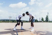 Vue latérale de gars afro-américains jouant au basket dans la journée brillante sur le terrain de jeu — Photo de stock