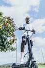 From below of African American sportive man riding on electric scooter in bright cloudy day — Stock Photo