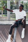Nachdenklicher afrikanisch-amerikanischer Sportler macht bei hellem Tag Selfie mit Handy auf Spielplatz-Zaun — Stockfoto