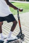 Cropped image of African American sportive man riding on electric scooter in bright cloudy day — Stock Photo