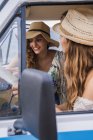 Group of touristic charming ladies in hats studying map for navigation in trip in van — Stock Photo