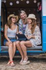 Charmante langhaarige Frauen im Sommer tragen digitale Tablets und unterhalten sich lächelnd im Autosalon — Stockfoto