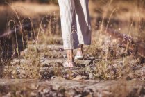Mujer de pelo largo de pie sobre ferrocarriles cubiertos de hierba seca - foto de stock