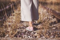 Langhaarige Frau steht auf mit trockenem Gras bewachsenen Gleisen — Stockfoto