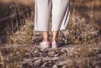 Mulher de cabelos compridos em pé em ferrovias cobertas de grama seca — Fotografia de Stock