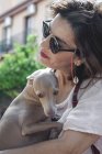 Vue latérale d'une femme heureuse câlinant son chien tout en se reposant ensemble à Marbella — Photo de stock