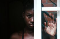 Mulher negra perturbada em pé atrás da janela — Fotografia de Stock