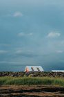 Pintoresco paisaje de acogedora casa linda en campo verde sin fin en Islandia en día nublado en Islandia - foto de stock