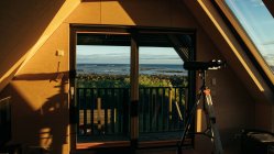 Pequeña habitación acogedora con telescopio de ventana para ver las estrellas y el paisaje increíble en el día soleado en Islandia - foto de stock