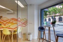 Сучасний дизайн інтер'єру світлого просторого офісу, зосередженого скляною стіною зі зручними жовтими стільцями та сірими барними стільцями за дерев'яними столами — стокове фото