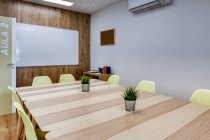 Design de interiores modernos de escritório espaçoso luz zoneada por parede de vidro com confortáveis cadeiras amarelas e bancos de bar cinza em mesas de madeira — Fotografia de Stock