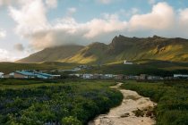 Живописный ландшафт пути между уютными милыми домами в горной долине Исландии в пасмурный день — стоковое фото