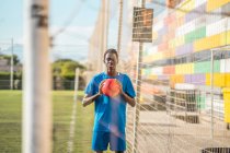 Preto adolescente segurando laranja no campo de futebol — Fotografia de Stock