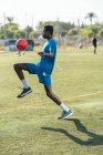 Black young man juggling football ball on green lawn — Stock Photo