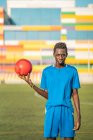 Adolescente preto com bola de futebol contra assentos de estádio — Fotografia de Stock