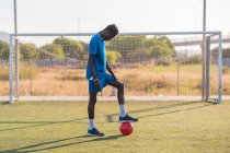 Jogador de futebol preto com bola de pé no estádio — Fotografia de Stock