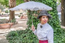 Винтажная леди с зонтиком, отдыхающая в саду — стоковое фото