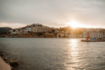 Vista aerea del porto di mare con edifici ben alloggiati con tetti rossi e molo con barche sulla costa con acqua scura e cielo grigio nuvoloso al tramonto — Foto stock