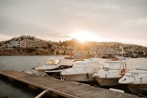 Морський порт з білими яхтами і човнами в місті з будівлями на пагорбах на красивому заході сонця з хмарним небом — стокове фото