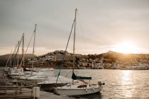 Sea port with white yachts and boats in city with buildings on hills at beautiful sunset with cloudy sky — Stock Photo