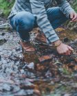 Dal basso di maschio accovacciato su sentiero bagnato durante le passeggiate nella foresta autunnale — Foto stock