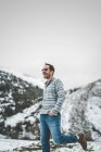 Casual man walking on winter field with hills covered with snow — Stock Photo