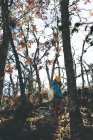 Vue de dessous d'une femelle méconnaissable marchant dans la forêt d'automne parmi les arbres — Photo de stock