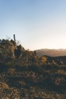 Vista laterale di giovane donna in usura attiva in piedi sul pendio della montagna al bellissimo tramonto autunnale — Foto stock