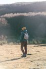 Vista posteriore del viaggiatore irriconoscibile in caldo abbigliamento attivo con zaino attraversando campo vuoto erba secca — Foto stock