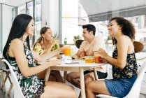 Diverse friends resting with smoothies sitting in cafe — Stock Photo