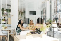 Разнообразные друзья с фруктовыми коктейлями сидят в кафе — стоковое фото