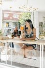 Signora con bevanda sana ascoltare musica nel caffè, persone in background — Foto stock