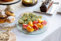 Dall'alto di sezioni di arance e pompelmi e kiwi su elegante tavola con biancheria bianca — Foto stock